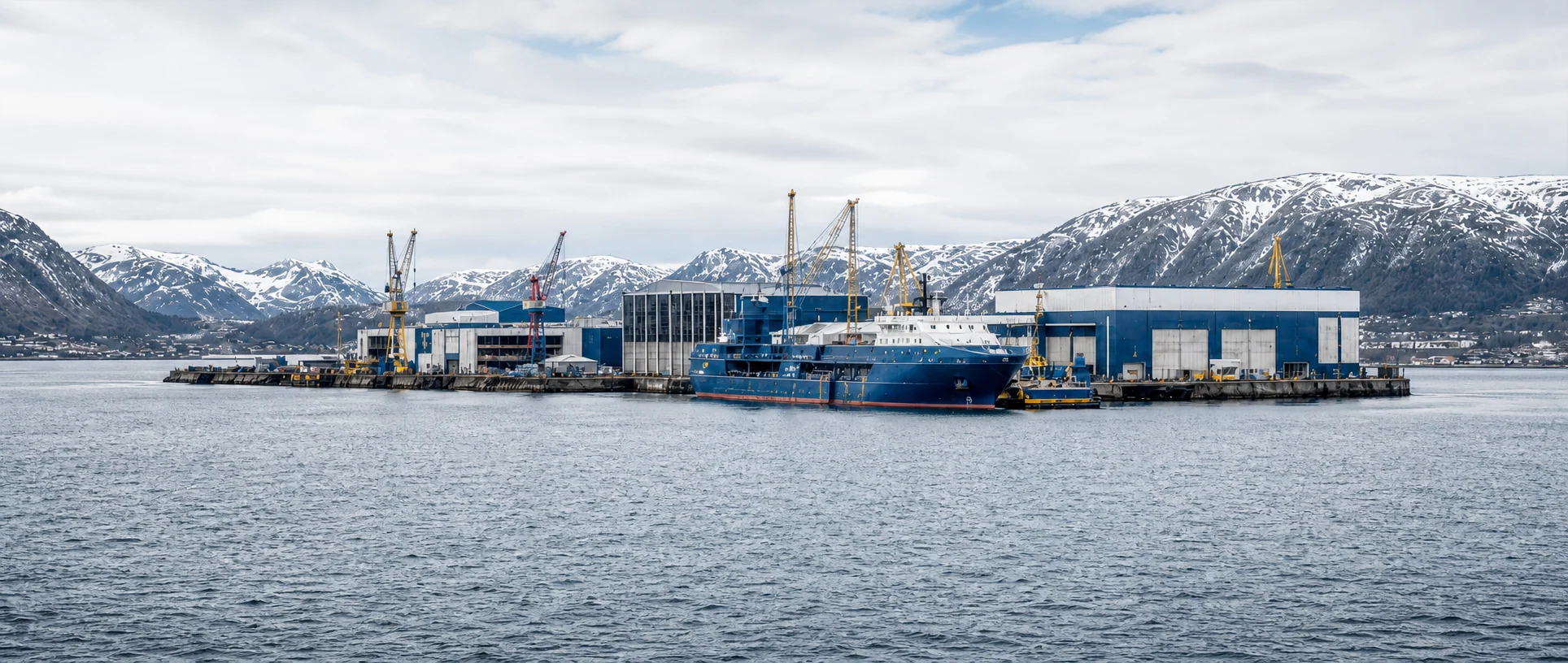 Norsk maritimt verft ved en fjord med fjell i bakgrunnen